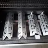 Four metal heat shields are arranged inside a grill. Anteprima dell’immagine prodotto