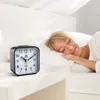 A woman sleeping peacefully in bed next to an alarm clock. Produktbild-Vorschau