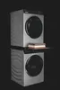 A stacked washing machine and dryer unit with a shelf and folded towels between them, set against a black background. Podgląd zdjęcia produktu