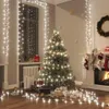 A Christmas tree decorated with lights and ornaments, surrounded by gifts and festive decorations in a room. Náhled obrázku produktu