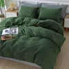 A bed with dark green bedding, pillows, and a book on the bed. Produktbild-Vorschau