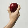 A hand holding a red apple against a white background. Anteprima dell’immagine prodotto