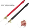Two embroidery hooks, one red and one black, are shown against a white background. A close-up inset shows a hand holding the red hook. Podgląd zdjęcia produktu