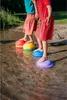 Two children are playing on stepping stones in shallow water. Voir les images du produit