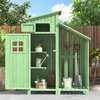 A green wooden garden shed filled with gardening tools and accessories, set against a blurred background of trees and a wooden fence. Náhled obrázku produktu