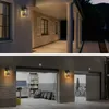The image shows two scenes: the top shows a house exterior with wall lights illuminating a porch, and the bottom shows a garage exterior with wall lights illuminating the garage doors. Produktbild-Vorschau