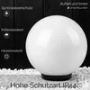 A white spherical lamp is shown outdoors on gravel and stone, with a black wooden fence in the background. Text overlays describe its features. Podgląd zdjęcia produktu