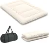 A beige futon mattress is shown unfolded and then folded, alongside a black duffel bag. Produktbild-Vorschau