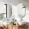 A modern bathroom vanity with two oval mirrors above two vessel sinks, featuring plants and a soap dispenser. Podgląd zdjęcia produktu