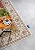 A rug is shown on a floor with a small table holding a plant and coffee. Voir les images du produit