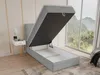 A bed with its storage compartment open, in a room with a large window overlooking a natural landscape. Produktbild-Vorschau