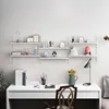 A white desk with a lamp, books, and a vase of flowers, set against a wall with white modular shelves displaying various decorative items. Voir les images du produit