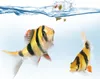 Two tiger barbs are swimming in clear water, with food splashing into the water from above. Produktbild-Vorschau
