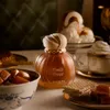 A perfume bottle is displayed on a table with desserts and drinks. Voir les images du produit