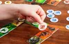 A hand is placing a token on a board game. Voir les images du produit