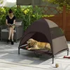 A woman reads a book while sitting on a chair next to a dog bed with a tent-like cover, where a dog is resting. Anteprima dell’immagine prodotto
