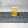 A yellow LEGO door with a white frame is placed on a gray LEGO baseplate. Produktbild-Vorschau