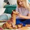 A young girl is playing with a stuffed horse toy on the floor. Podgląd zdjęcia produktu