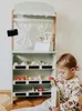 A young child is playing with a wooden market stall toy. Produktbild-Vorschau