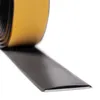A close-up, angled view of a roll of black self-adhesive tape with a yellow protective backing being peeled back. Podgląd zdjęcia produktu