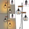 A collage of images showing a two-flame floor lamp with black metal cage shades and wooden accents, with close-ups of the light switches. Produktbild-Vorschau
