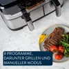 A close-up shot of a modern air fryer with a meal of steak, tomatoes, and broccoli on a plate next to it. Produktbild-Vorschau
