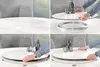 A collage of four images showing a round dining table with a rotating serving tray, demonstrating its functionality. The table has a white marble-like ceramic top and a black metal base. Chairs are visible in the background. Produktbild-Vorschau