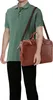 A person wearing a green polo shirt and black pants is holding a brown leather briefcase. Produktbild-Vorschau