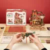 A 3D wooden puzzle kit is displayed with its box and assembled model. Parts of the puzzle are laid out, and a person is holding a partially assembled component. Podgląd zdjęcia produktu