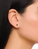 Close-up of a woman's ear wearing a small black stud earring. Anteprima dell’immagine prodotto