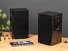Two wooden speakers are placed on a wooden table, with a smartphone in front of them. Náhled obrázku produktu