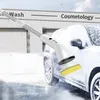 A white electric cleaning brush with a telescopic handle is being used to clean a car covered in snow and foam. Voir les images du produit