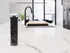 A pop-up power strip is installed on a white marble kitchen island, with a sink and faucet in the background. Náhľad obrázku produktu