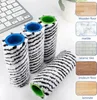 Four cleaning roller brushes with zebra-like patterns and colored plastic caps are arranged on a white surface, with a keyboard in the background. To the right, there are swatches of different flooring materials with text labels. Produktbild-Vorschau