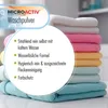 A stack of folded towels in various pastel colors, with a circular overlay containing text describing the features of a laundry detergent. Produktbild-Vorschau