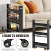 A narrow shelving unit with four shelves, filled with various items like bottles, jars, and packaged goods, is placed next to a sofa. The unit has wheels and a handle. The image also includes close-up diagrams of the wheels and text overlays. Podgląd zdjęcia produktu
