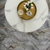 A close-up overhead view of a round marble-patterned coffee table with decorative items on it, placed on a marble-patterned rug. Produktbild-Vorschau