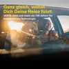 Two women are smiling and looking out of a car window during a sunny road trip. Produktbild-Vorschau