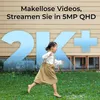 A young girl runs in front of a house with large blue numbers '2K+' superimposed. Produktbild-Vorschau