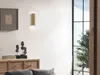 A modern living room interior with a wall lamp, a wooden cabinet, and decorative busts. Produktbild-Vorschau