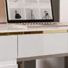 A close-up view of a white, high-gloss desk with a gold accent strip and a laptop open on its surface. Produktbild-Vorschau