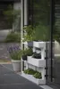 A white wooden pallet planter filled with various herbs and plants, placed next to a modern building with large windows. A pot of lavender is also visible. Voir les images du produit