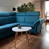 A modern living room with a teal sectional sofa and two white, round coffee tables. Produktbild-Vorschau