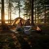A couple camping by a lake at sunset, with a tent and campfire. Anteprima dell’immagine prodotto