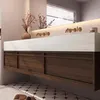 A modern bathroom vanity with a white countertop, dark wood cabinets, and gold faucets. Anteprima dell’immagine prodotto