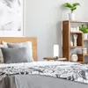 A bedside table with a lamp and decorative items next to a bed. Produktbild-Vorschau