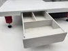 A close-up view of a white sewing machine with an open drawer, showing its internal compartments. Náhľad obrázku produktu