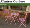 A pink bistro set with two chairs and a table on a wooden deck, with a building in the background. Produktbild-Vorschau