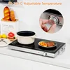 A close-up shot of a portable induction cooktop on a kitchen counter, with food and bread in the background. A hand is shown adjusting the temperature dial. Produktbild-Vorschau