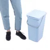 A person's legs and feet are shown next to a blue trash can. Produktbild-Vorschau